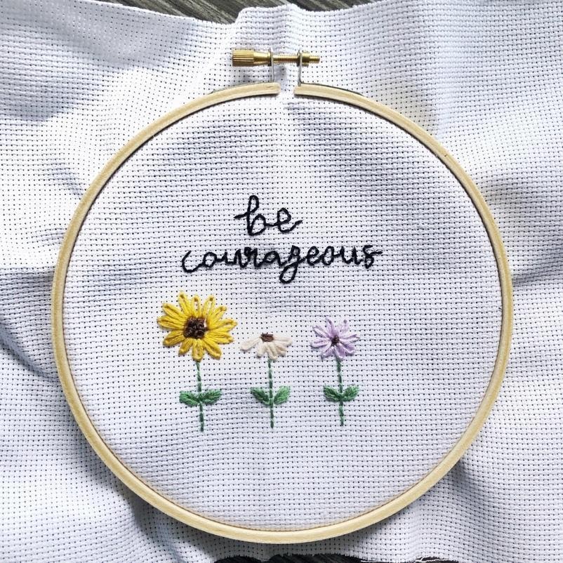 embroidered art with the text "be courageous" and 3 flowers